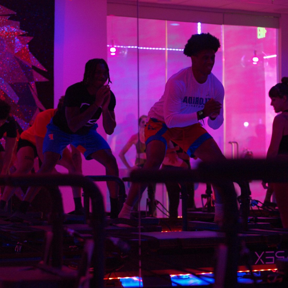 Students in a squat on the APEX Xformers under pink light