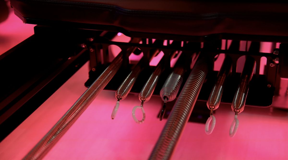 The springs under an APEX machine in pink studio light